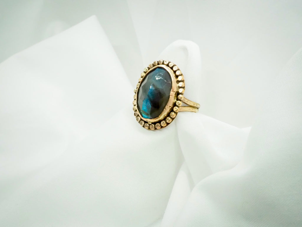 "A stunning gold-filled ring featuring a mesmerizing labradorite gemstone in a size 10. The ring has a simple yet eye-catching design with a sleek band and a stunning labradorite stone as the centerpiece. The labradorite displays a brilliant iridescent quality, capturing the light with every movement. A beautiful and timeless piece that adds sophistication to any outfit."