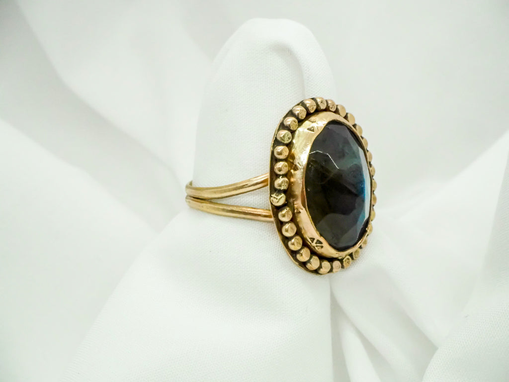"A stunning gold-filled ring featuring a mesmerizing labradorite gemstone in a size 10. The ring has a simple yet eye-catching design with a sleek band and a stunning labradorite stone as the centerpiece. The labradorite displays a brilliant iridescent quality, capturing the light with every movement. A beautiful and timeless piece that adds sophistication to any outfit."