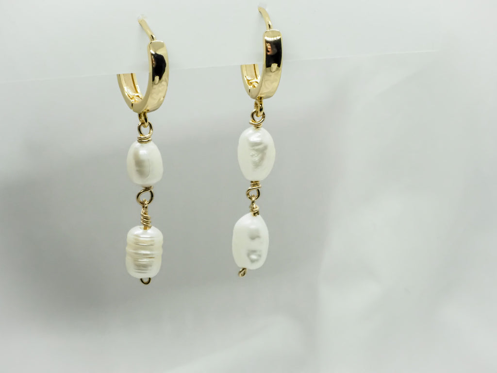 "A pair of elegant dangle earrings featuring fresh water pearls and 14k gold-filled huggie hoops. The earrings have a simple yet sophisticated design with the pearls hanging from delicate gold-filled huggie hoops. The fresh water pearls have a soft and lustrous appearance, adding a touch of luxury and grace to the earrings. These earrings are perfect for dressing up or adding a touch of sophistication to any casual outfit."