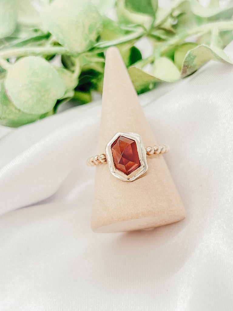 "A beautiful 14k gold-filled ring featuring a stunning hexagonal-shaped Hessonite garnet in a size 8. The ring has a unique design with the hexagonal garnet set in a 14k gold-filled band, creating a visually interesting and eye-catching look. The Hessonite garnet displays a rich orange-brown color that is further highlighted by the gold-filled setting. This is a versatile and timeless piece that can be worn every day or for special occasions."